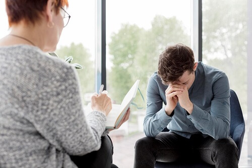 A sad man sitting in front of his therapist with is head down