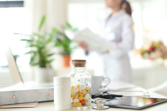 A psychiatrist standing next to bottles of medications writing a script